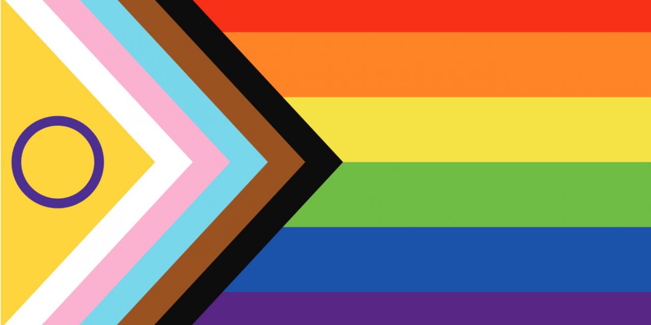 Intersex-Inclusive Progress Pride Flag: Regenbogenstreifen mit einem Pfeil aus weißen, rosa und hellblauen sowie braunen und schwarzen Streifen und einem violetten Kreis auf gelbem Feld